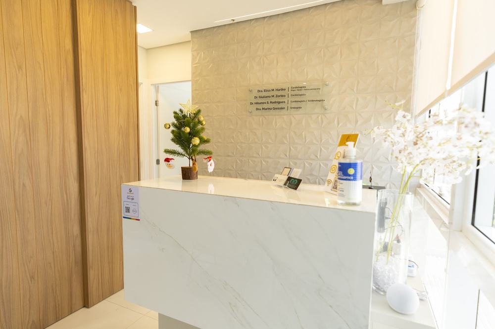 Recepção do consultório, com bancada em mármore e orquídea